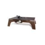 A brown Exxentric kBox 4 Lite Platform with a black resistance strap and metallic wheel for flywheel training. The rectangular platform features sturdy legs and #KBOX4 on the side.