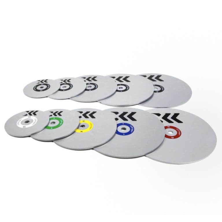 A set of ten Exxentric Flywheel weight plates for kBox 4, featuring silver metal plates with color-coded inner rings and arrow designs, arranged in descending size order.