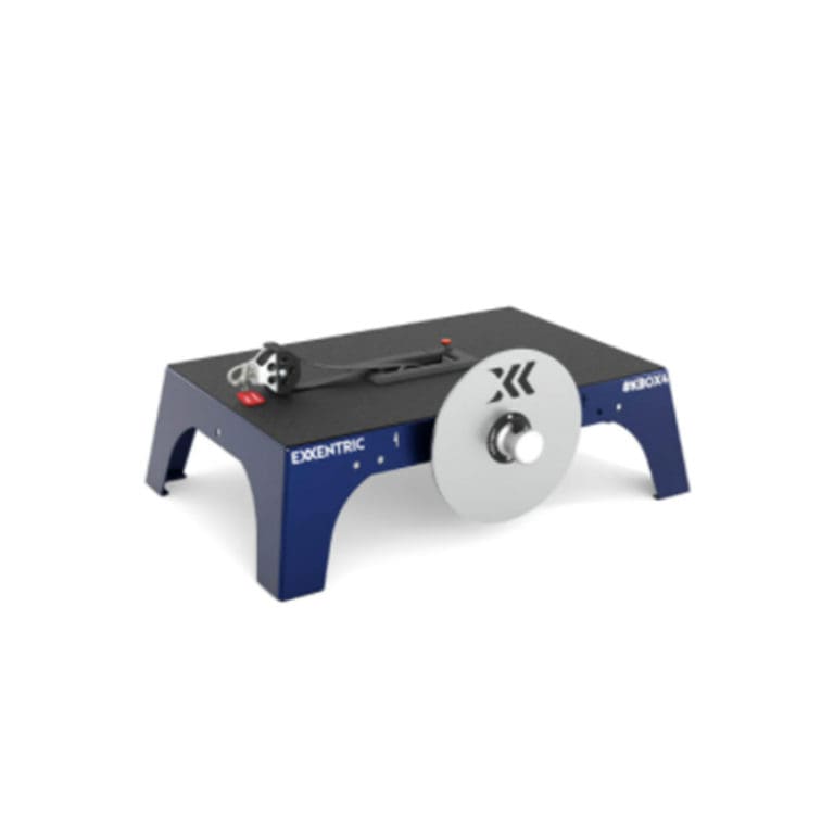 A compact, blue Exxentric kBox 4 Active Advanced Plus System features a central flywheel and handle for strength training, with the Exxentric logo on its side. It is placed on a plain white background.