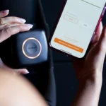 A person holds a small black AirBands 2.0 device with a glowing ring next to a smartphone showing an app with calibration options for arms and legs.