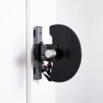 The wall-mounted door-opening mechanism combines a sleek, minimalist design with a black circular component and metallic support, reminiscent of the Exxentric kPulley GOs high-tech efficiency, seamlessly merging form and function.