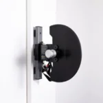 The wall-mounted door-opening mechanism combines a sleek, minimalist design with a black circular component and metallic support, reminiscent of the Exxentric kPulley GOs high-tech efficiency, seamlessly merging form and function.