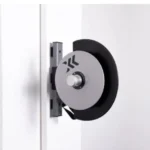 A wall-mounted retractable belt barrier echoes the sleek design of Exxentrics kPulley GO, featuring a silver circular mechanism holding a black belt. It extends smoothly to block or direct passage, blending seamlessly into the minimalistic white wall.