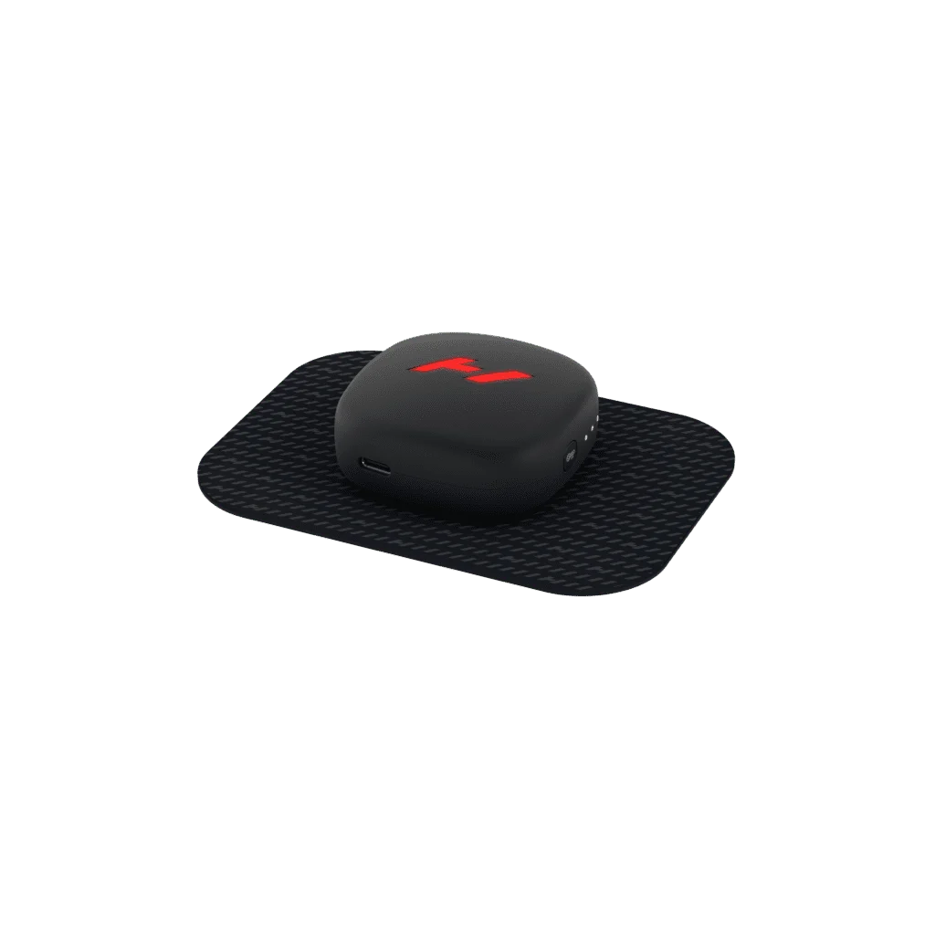 The Venom Go, a sleek black massage device, features a red logo and rests on a rectangular black mat. Enhanced with heat and vibration technology and including a USB charging port on the side, it sits against an elegantly simple plain black backdrop.