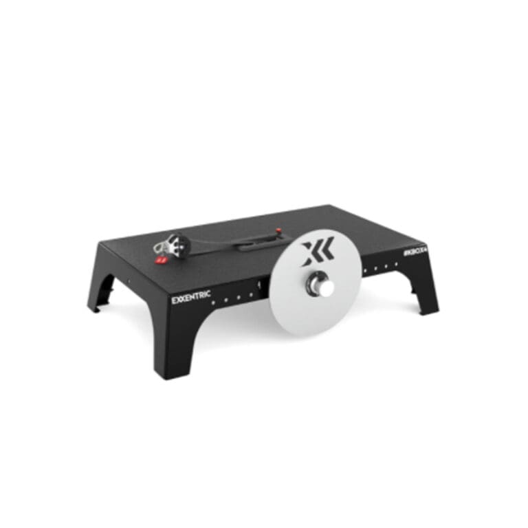 An exercise machine featuring a flat black base with a silver resistance disc and a handle attached to a cord. The device is labeled Exxentric kBox4 on the side, designed for strength training.