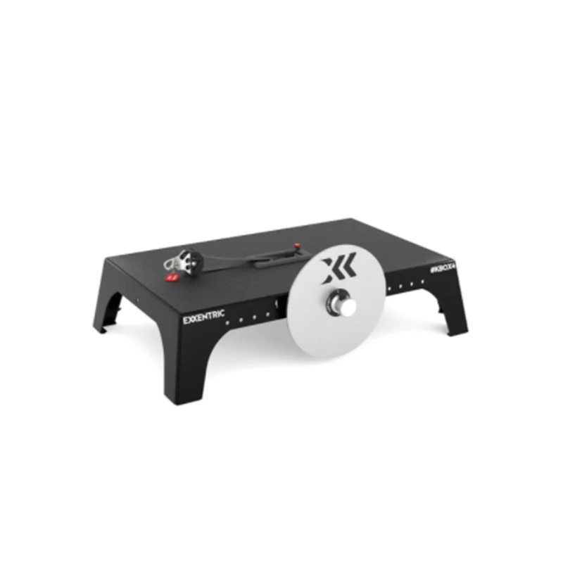 An exercise machine featuring a flat black base with a silver resistance disc and a handle attached to a cord. The device is labeled Exxentric kBox4 on the side, designed for strength training.