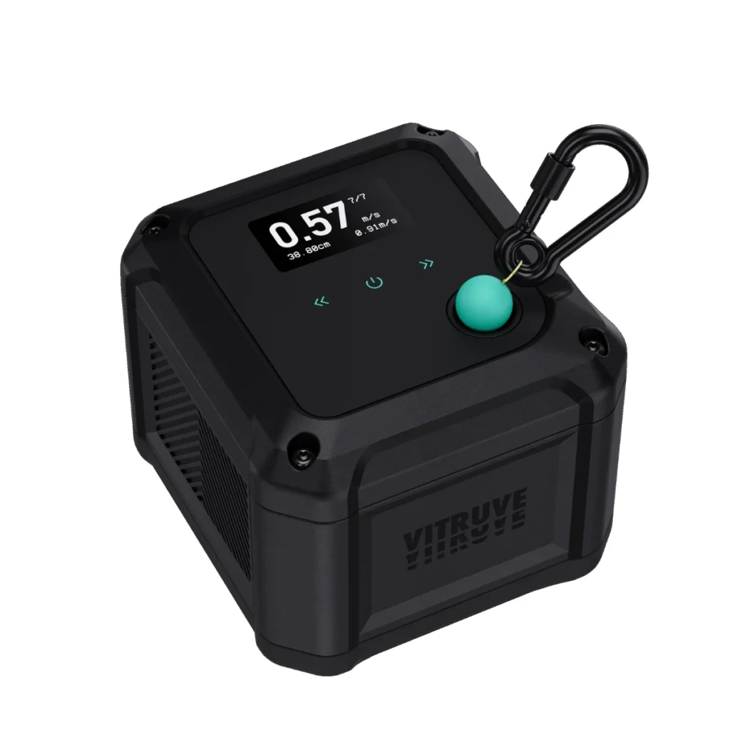 The Vitruve VBT Encoder is a black, cube-shaped device featuring a digital numeric display, a green button, a top-corner black carabiner, and the "VITRUVE" brand name printed on its side.