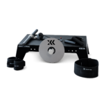 The Exxentric kBox Lite Starter System features a central metal flywheel, a black rectangular base labeled "Exxentric KBox," and various black fitness accessories including straps and handles arranged around it.