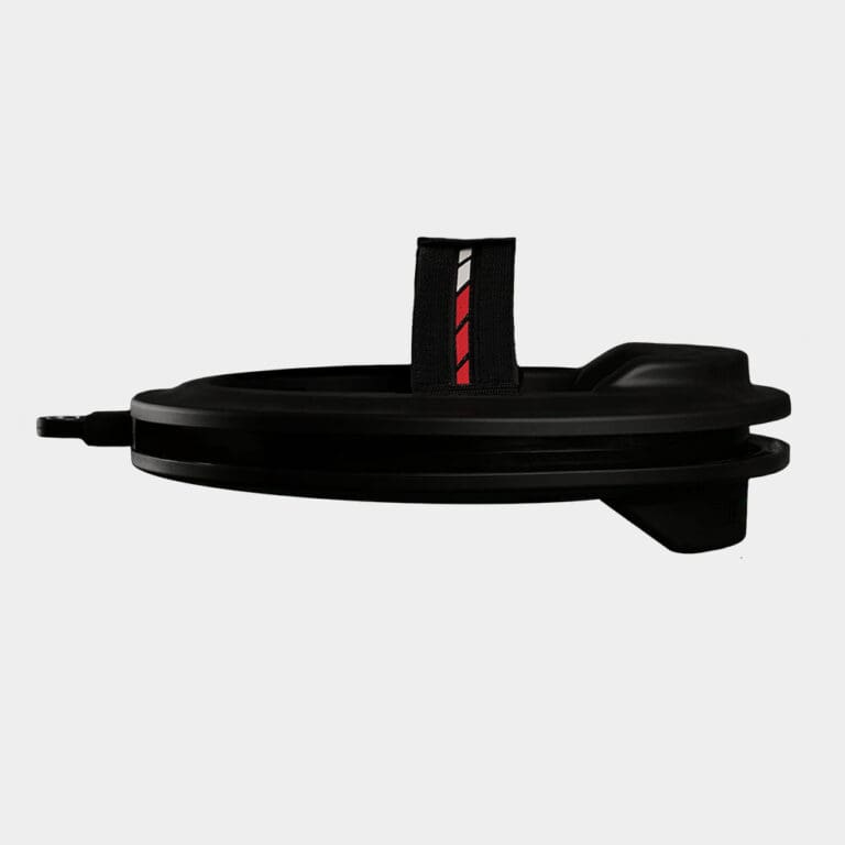 Side view of the Iron Neck 3.0: a black, round object with a handle featuring a black strap adorned with red and white stripes, set against a plain gray background.