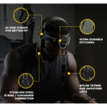 In a dimly lit gym, someone wears the Iron Neck Alpha Harness, which includes two side straps for a snug fit, ultra-durable stitching, a stainless steel D-ring with carabiner connection, and a nylon tether for smoother lifts.
