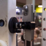 A smartphone is securely attached to a gym rack with the OVR Performance Velocity and Jump Bundle, while workout equipment appears blurred in the background.