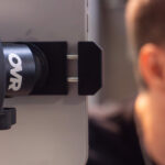 A close-up shows someone using an OVR Magnetic Phone Mount attached to the side of a tablet or screen, with their face slightly out of focus on the right.