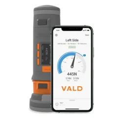 A VALD Dynamo Plus handheld dynamometer stands behind a smartphone showing a strength measurement screen with a 445N left shoulder reading, gauge, and the VALD logo on display.