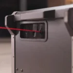 A close-up of the TAPEX shows a rectangular slot with brush bristles on a matte gray container, and a red cable running through the opening.