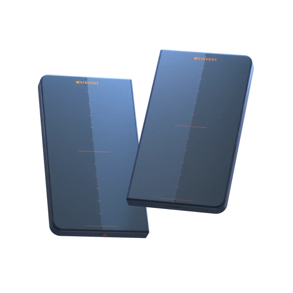 Two dark rectangular KINVENT K-Force Plates with orange markings and "KINVENT" at the top are positioned side by side on a white background.