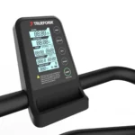 Close-up of a TRUEFORM Trainer digital display showing speed, distance, time, calories, pace, and heart rate with control buttons like start and sync on curved black handlebars.
