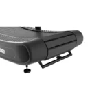 Close-up of the TRUEFORM Trainer, a modern curved black treadmill featuring a slatted running surface and minimalistic design, with focus on its front corner and base.