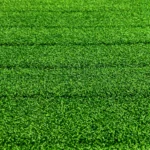 Close-up of TRUEFORM.TRAINER™ Curved Treadmill Turf: vibrant green artificial grass with textured blades and subtle horizontal lines marking turf sections.
