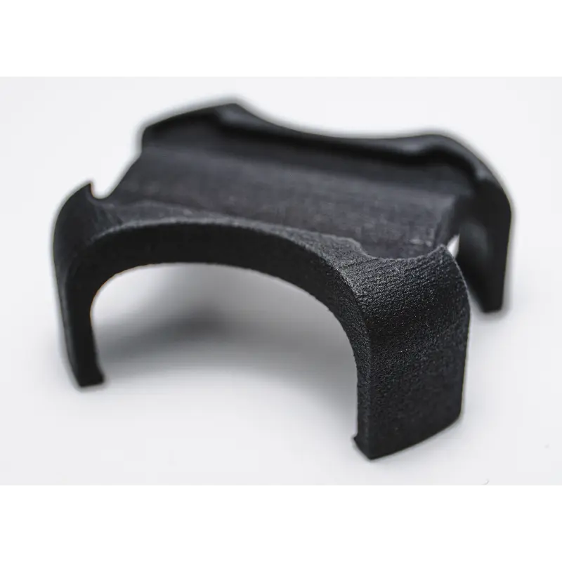 Close-up of the black, curved Enode Pro / Exxentric Flywheel Adapter, a small 3D-printed object with a textured surface and four arms, set against a sleek white background.