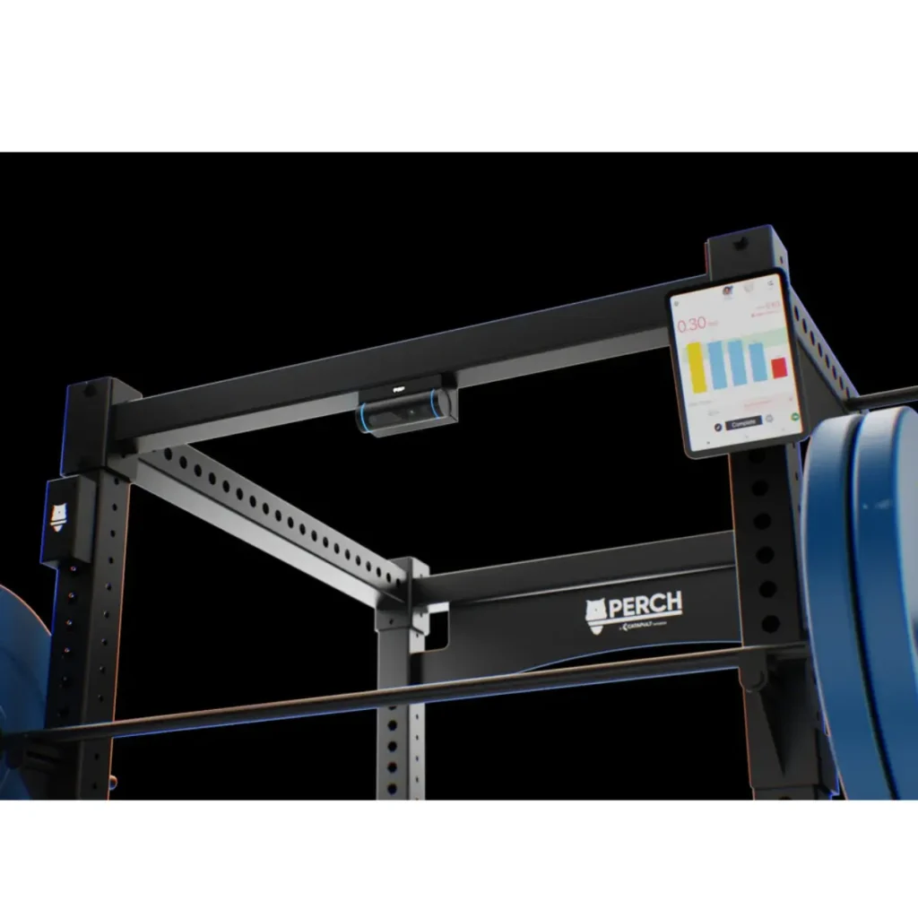 A close-up of a gym squat rack with a Perch Camera mounted and its digital screen displaying workout data, including a timer and bar graphs. Blue weight plates are loaded on the barbell.