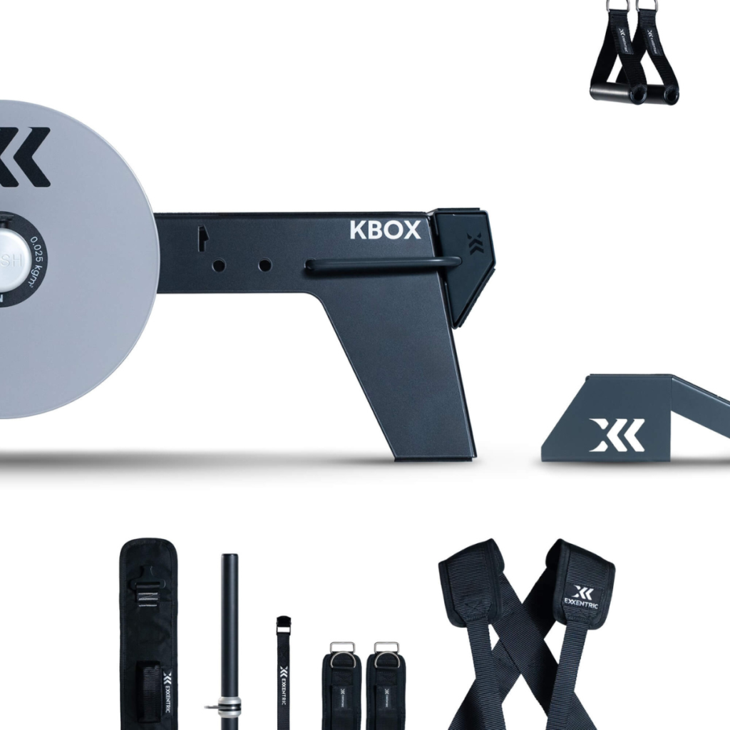 The kBox Advanced System, featuring a flywheel platform, resistance straps, handles, bar, and foot supports, is neatly arranged on a white background.